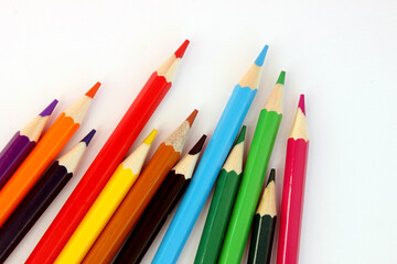 Colored pencils on a white background. Lots of different colored pencils. Colorful pencil. Pencils are sharp. Pencils lie diagonally in the lower left corner. Close-up. Copy space. Background. Flatlay