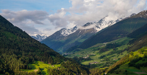 Fototapeta premium Scenic view of beautiful Swiss Alps mountains. Canton du Valais, Switzerland. Picturesque Alpine village in background. Swiss Alps with snow on top. Switzerland in summer. Alpine landscape