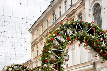 View of street decorations with lights on Kamergerskiy street with red and white flowers in city center of Moscow for Christmas and New Year Eve. Historical, old Russian building in the background.