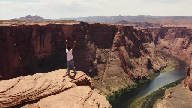 Travel photographer standing on the edge of Horseshoe Bend, a river in canyon, scenic Arizona
