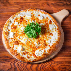 Delicious round pizza on a wooden stand on the table