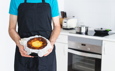 Man in black apron showing a cheesecake. Kitchen concept.