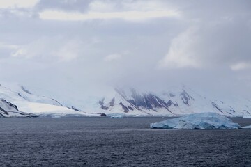 Iceberg in dark ocean before glacier landscape, Antarctica