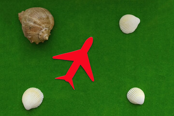 The plane is red, sea shells on a green background. Tourism, travel, resort, vacation.