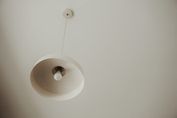 White industrial and minimalist lamp hanging on a white roof. Minimalist concept. Minimalist stock photos. Aesthetic composition.