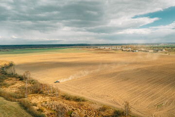 Aerial View. Tractor Plowing Field In Spring Season. Beginning Of Agricultural Spring Season. Cultivator Pulled By A Tractor In Countryside Rural Field Landscape