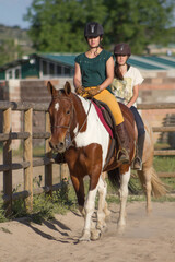 Obraz premium Sisters with happy actitude at a horse riding lesson looking at camera.