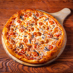 Delicious round pizza on a wooden stand on the table
