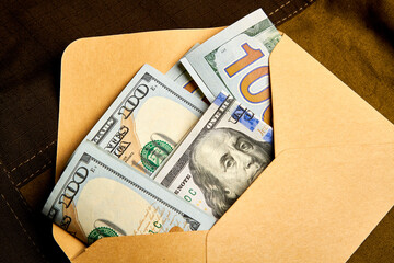 Hundred dollar bills in a paper envelope. Receiving money in an envelope. Black bookkeeping. Giving a bribe.