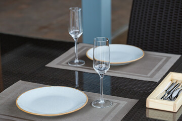 Served table in a restaurant for two. Blue plates for food, two glasses. Romantic evening concept