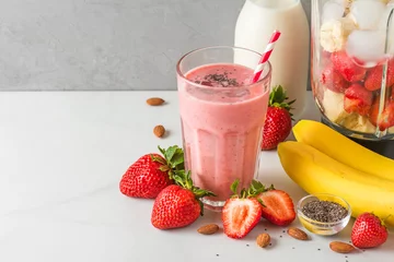 Selbstklebende Fototapeten Glass of strawberry and banana vegan smoothie or milkshake made of almond milk with fresh juicy ingredients in blender © samael334