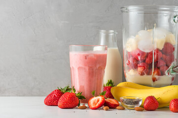 Glass strawberry and banana smoothie or milkshake with fresh juicy ingredients in blender for...