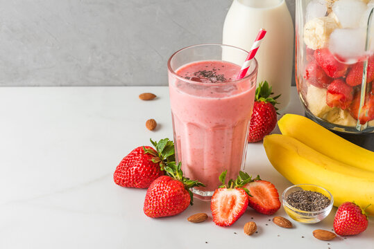 Glass of strawberry and banana vegan smoothie or milkshake made of almond milk with fresh juicy ingredients in blender