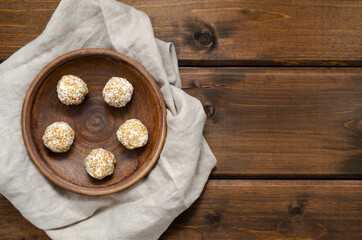 Homemade raw vegan sweets energy balls in coconut shavings in ceramic plate on old wooden table
