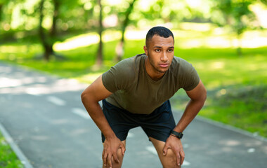 Handsome black guy in sportswear resting after his morning run at park