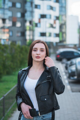 beautiful stylish young girl in a black leather jacket on the streets