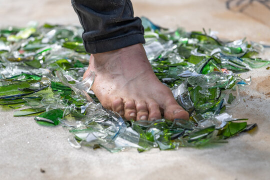 Fakir mit Fuss auf und &uuml;ber Glasscherben