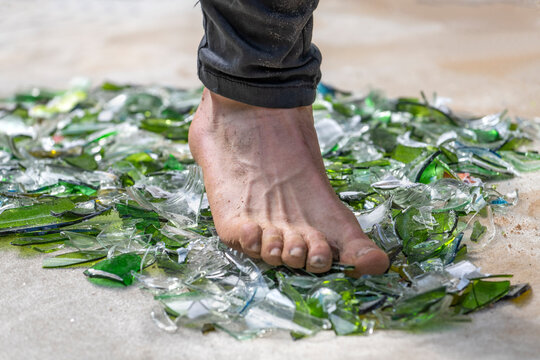 Fakir mit Fuss auf und &uuml;ber Glasscherben