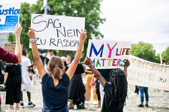 Black Lives Matters Protest-  Black girl holds sign that My Life Matters, White girl holds German sign