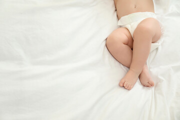 Cute little baby in diaper on bed, top view. Space for text
