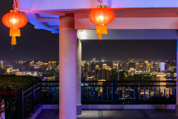 View of the night city of Sanya through a gazebo with Christmas lights in Luhuitou Park, Sanya,...