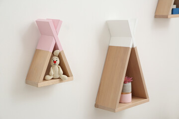 Funny wigwam shaped shelves with toys on white wall. Baby room interior design © New Africa