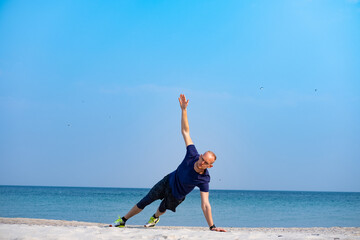Obraz premium Young male athlete training in sunny day on the beach