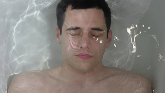 Man lies under water in the bath