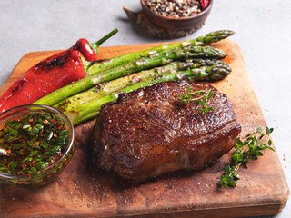 juicy roasted beef steak, pepper, asparagus, on a wooden board close up, sauce