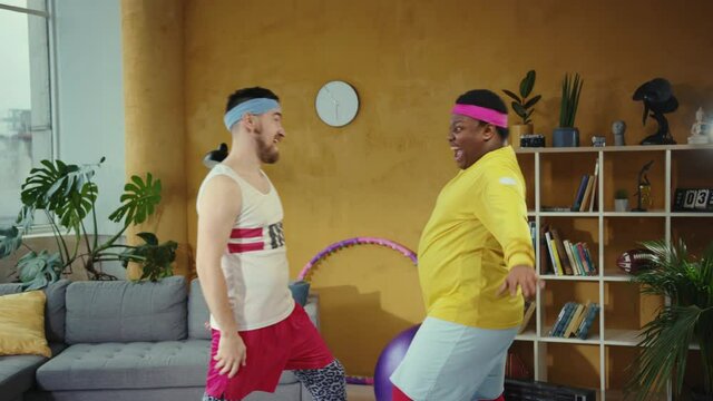 Funny two multi-race fitness men greeting each other, slapping their hands and bumping having good time home training. Best friends. Buddies. Friendship concept.
