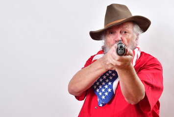 Determined looking old man with a sawed off rifle, wearing patriotic colors, and a floppy western hat pointing his weapn right at the camera..Crazy old man has that "Get off my lawn" look