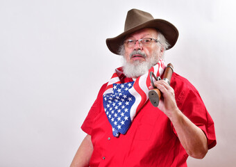 Serious looking man, armed with a sawed off rifle, wearing patriotic colors, eyeglasses and a floppy western hat. - obrazy, fototapety, plakaty