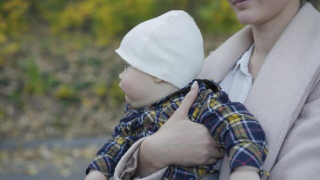 Portrait of the cutiest baby boy with blue eyes looks around on mother's hands