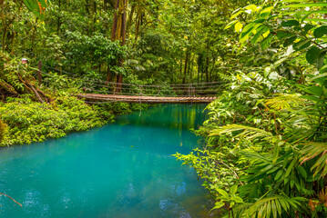 Rio Celeste with turquoise, blue water and small wooden bridge across the river Tenorio national park Costa Rica. Central America.