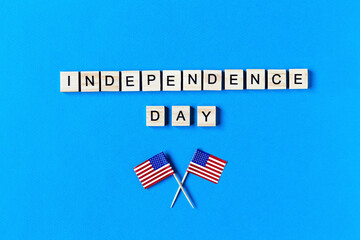 Independence Day inscription in wooden letters on a blue background. Happy Independence Day. The 4th of July. American flags. USA Independence day. copy space. top view