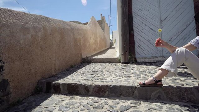 Woman smell spring flower on visitt of romantic Santorini island