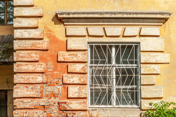 window in an old painted yellow brick house