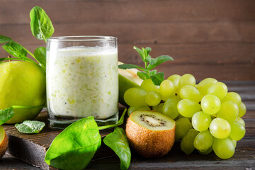 glass of  yogurt with fresh kiwi, Apple, green grapes,  spinach and mint on a wooden