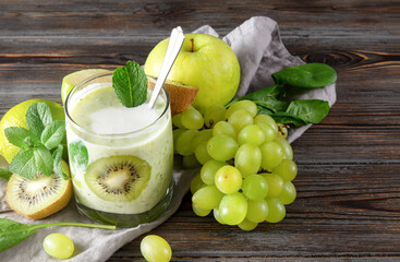 Cup of natural yoghurt with kiwi,  Apple, grapes and mint on a grey napkin on a brown wooden