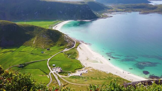 View from mountain Mannen over Haukland beach in Lofoten, Norway during a sunny summer day. Turquoise and blue ocean meeting the white sand beach with the fjords in the background.