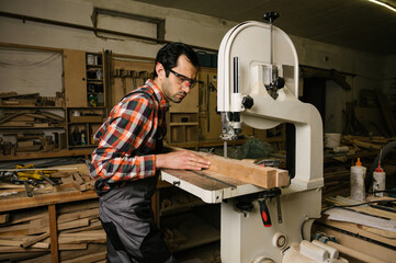 a man sawing a wooden board on a band saw