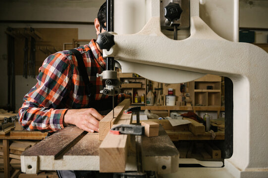 a man sawing a wooden board on a band saw