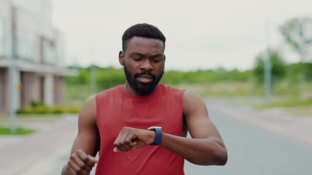 Active Black Runner Stops in the Street to Check His Heart Rate on Smartwatch. Portrait Healthy Afro-American Man Using Holographic Fitness Tracker While Running. 3D Render Animation.