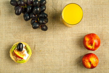 fruit tartlet with whipped cream and a glass of juice and fruits on the table on the tablecloth.