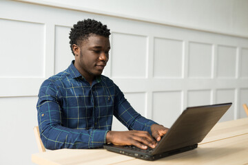handsome young african man at the table with laptop