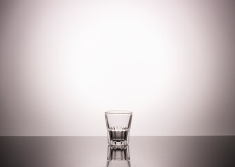 empty vodka shot glass with a beautiful gradient background