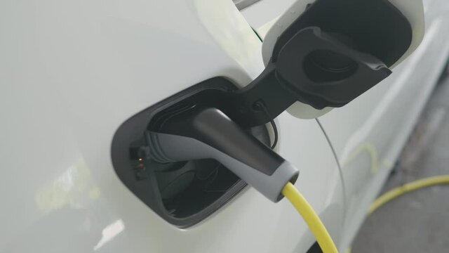 CU shot of a man's hands plugging in his eco-friendly electric vehicle