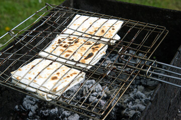 Grilled pita bread on the grill. Cooking over charcoal on a picnic.