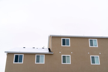 Exterior view of building with snowy pitched roof over wall with sliding windows