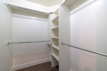 Hanging metal rods and storage shelves inside empty walk in closet of a new home